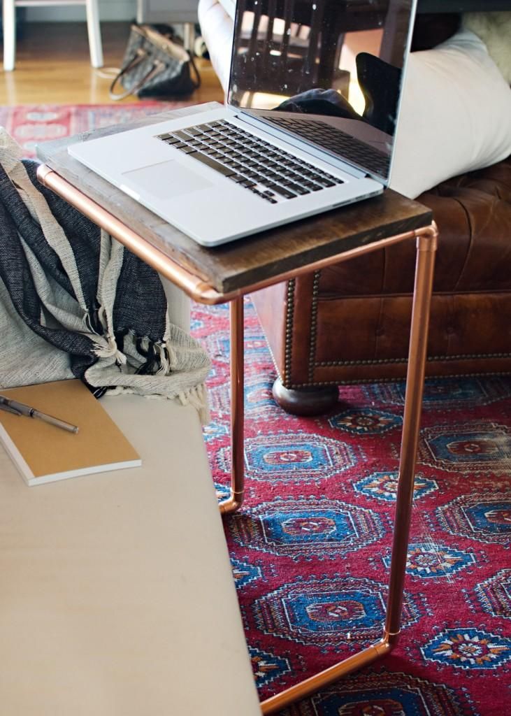 an open laptop computer sitting on top of a wooden table next to a couch in a living room