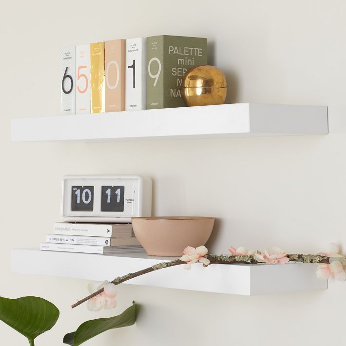 two white shelves with flowers and books on them