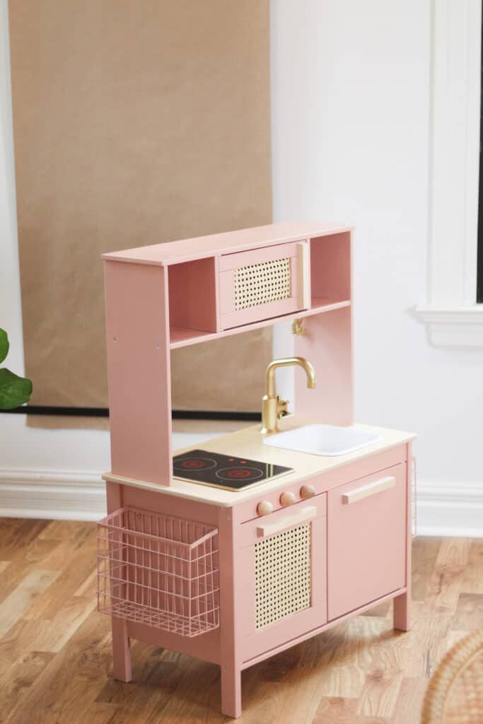 a pink play kitchen with a sink and oven