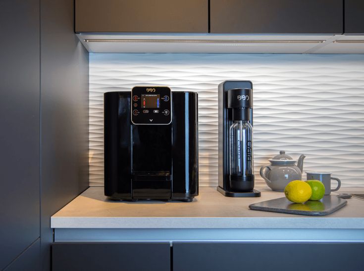 a coffee maker sitting on top of a counter next to lemons and a cup