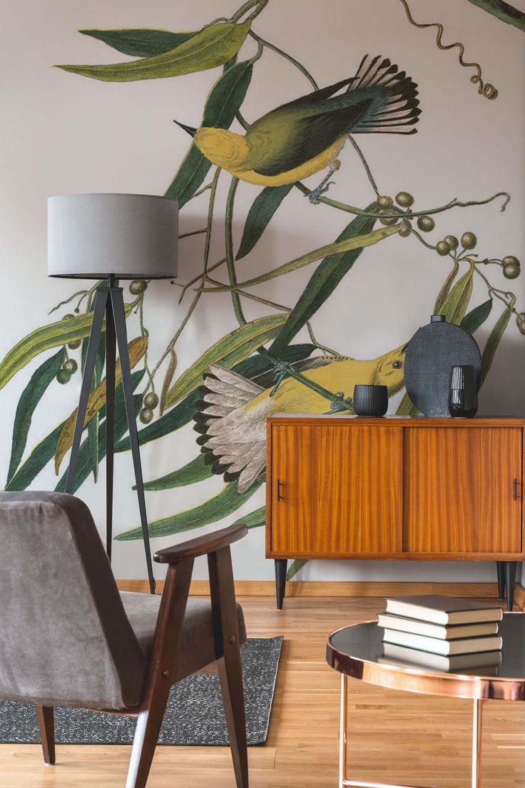 a living room with a bird mural on the wall next to a chair and table