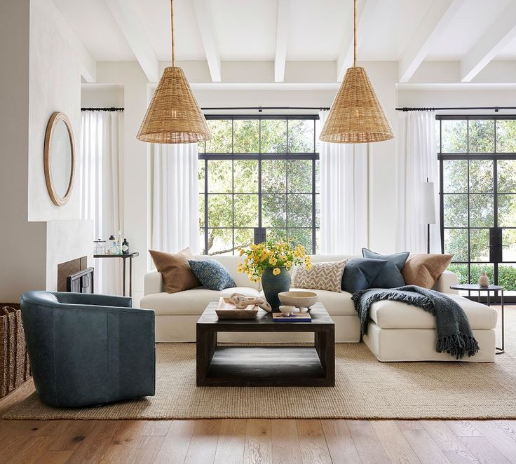 a living room filled with lots of furniture next to large windows and wooden floors in front of them