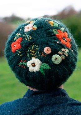 the back of a person wearing a green hat with flowers on it's side