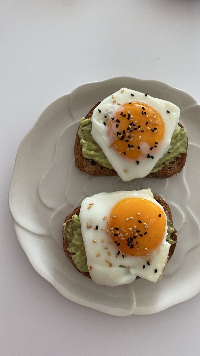 two eggs on toast with avocado and black sesame seeds