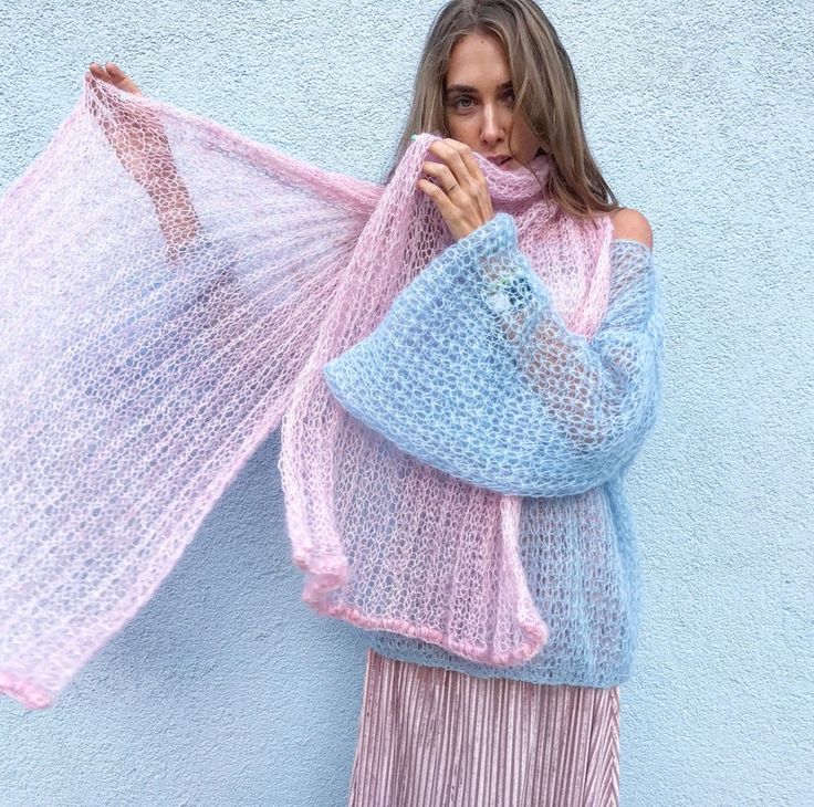 a woman in a pink and blue sweater is holding a shawl over her shoulder