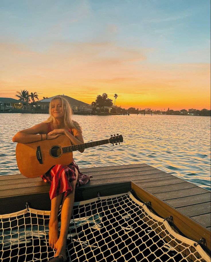 a woman sitting on top of a boat holding a guitar