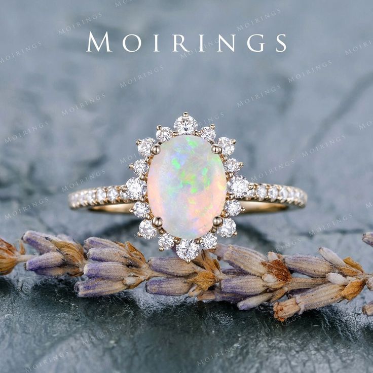 an opal and diamond ring on top of lavender flowers