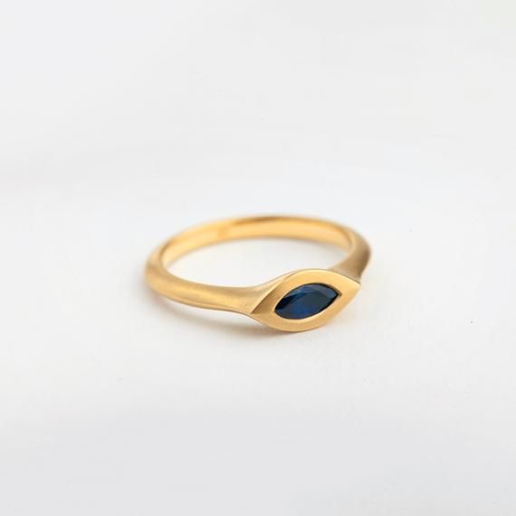 Our marquise sapphire engagement gold ring is a dainty ring with a large sapphire set within the ring. The ring has a thick band with a triangular profile and a sapphire set in a marquise structure. Metal: Solid Yellow 18k gold.Stone: Natural (Untreated) dark sapphire.Gold band width: app. 2 mm Gold band thickness: 2 mmRing bezel: 5X11 mmGold band width and thickness: app. 2 mmFinish: Matte / High polishPLEASE NOTICE Each gemstone can look a little different. There is a range of tones for natura Gold Marquise Sapphire Wedding Ring, Marquise Sapphire Promise Ring Jewelry, Marquise Sapphire Gemstone Ring, 14k Gold Marquise Cut Sapphire Ring As Gift, Sapphire Marquise Promise Ring, Yellow Gold Marquise Sapphire Ring Gift, Marquise Sapphire Ring In Yellow Gold As Gift, Marquise Sapphire Ring In Yellow Gold, Gold Marquise Sapphire Ring In 14k Gold