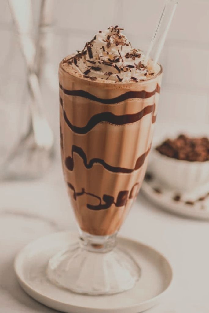 there is a chocolate milkshake with whipped cream on top and toppings in the glass