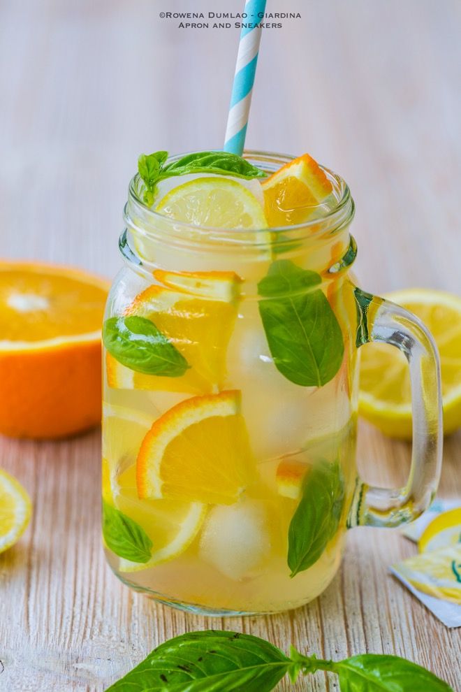 a mason jar filled with lemonade and mint leaves next to sliced oranges on a wooden table