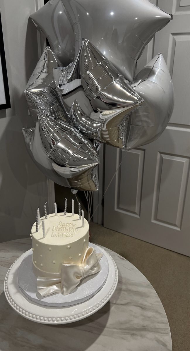 a birthday cake on a table with silver balloons