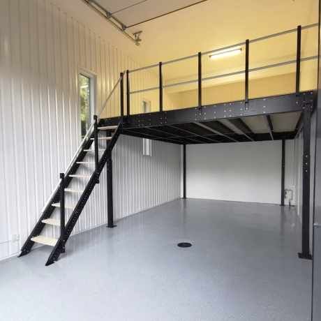 an empty garage with stairs leading up to the loft