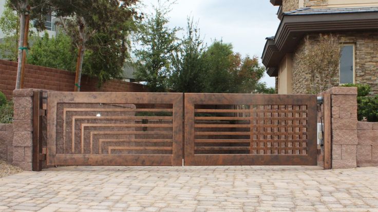 a wooden gate is shown in front of a brick wall and stone walkway with trees on the other side