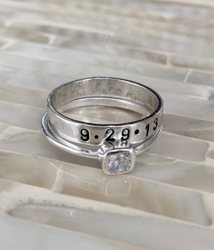 Custom promise ring- perfect four couples to wear before an engagement to symbolize love and devotion. Personalize with your name, date or short phrase and make a promise of commitment today. - Sterling silver stackable ring set. - Personalized, hand stamped ring measures 4mm. - Personalize with up to 12 characters. - Square CZ Ring. - heart stamp is available between names or end of phrase. - Available in sizes: 5, 6, 7, 8, 9. Please note, as you build a stackable ring set, keep in mind that th Silver Engraved Promise Ring With Birthstone, Personalized Silver Birthstone Ring For Anniversary, Engraved Ring For Anniversary, Customizable Silver Birthstone Ring For Wedding, Elegant Engraved Anniversary Ring With Stamped Detail, Personalized White Gold Birthstone Ring For Wedding, Elegant Engraved Anniversary Ring Stamped, Elegant Engraved Ring For Anniversary, Personalized White Gold Birthstone Wedding Ring