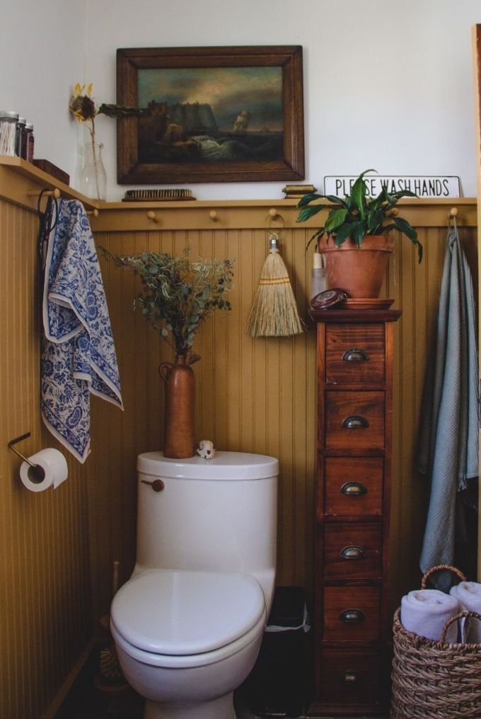 a white toilet sitting in a bathroom next to a wooden dresser and potted plant