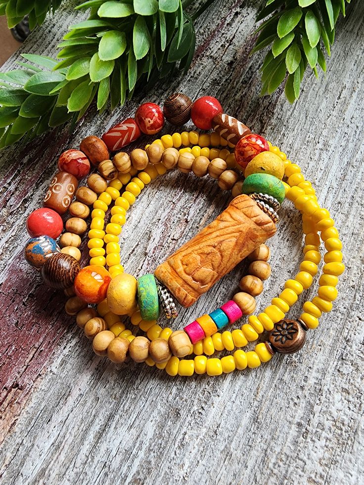 Beautiful and fun bohemian tribal mix bracelet trio in an array of spring and summer colors! Handcrafted clay beads in colors of rusty oranges and yellow, patterned wood beads and ceramics. The large handcrafted focal is 13x30mm with a rustic design flanked by two antique silver discs . A stretchy double wrap bracelet in small orange glass beads with a copper flower detail and a skinny bracelet in Natural wood rounds and colorful wood rondells. This bracelet will fit a bracelet size 6.75-7".  To Colorful Bohemian Heishi Beads Friendship Bracelets, Colorful Bohemian Friendship Bracelets With Heishi Beads, Multicolor Heishi Beads Bohemian Friendship Bracelets, Bohemian Multicolor Heishi Beads Friendship Bracelets, Colorful Bohemian Heishi Beads Bracelets, Bohemian Wrap Bracelet With Colorful Heishi Beads, Bohemian Multicolor Heishi Beads Bracelets, Colorful Bohemian Beaded Bracelets, Traditional Wooden Beads Bracelets For Beach