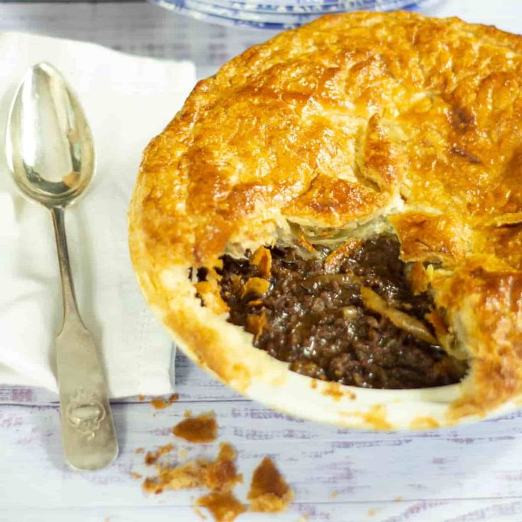 a close up of a pie on a plate with a fork and spoon next to it