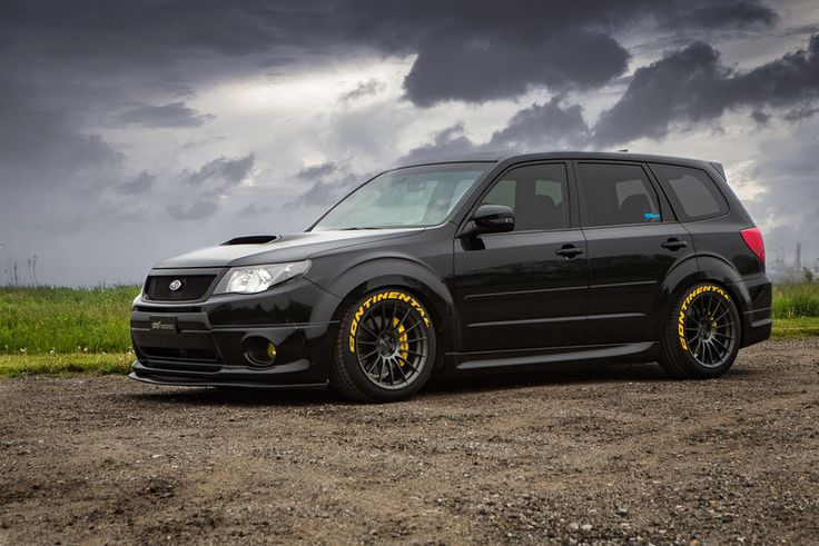 a black subarunt parked in the middle of a dirt road under a cloudy sky