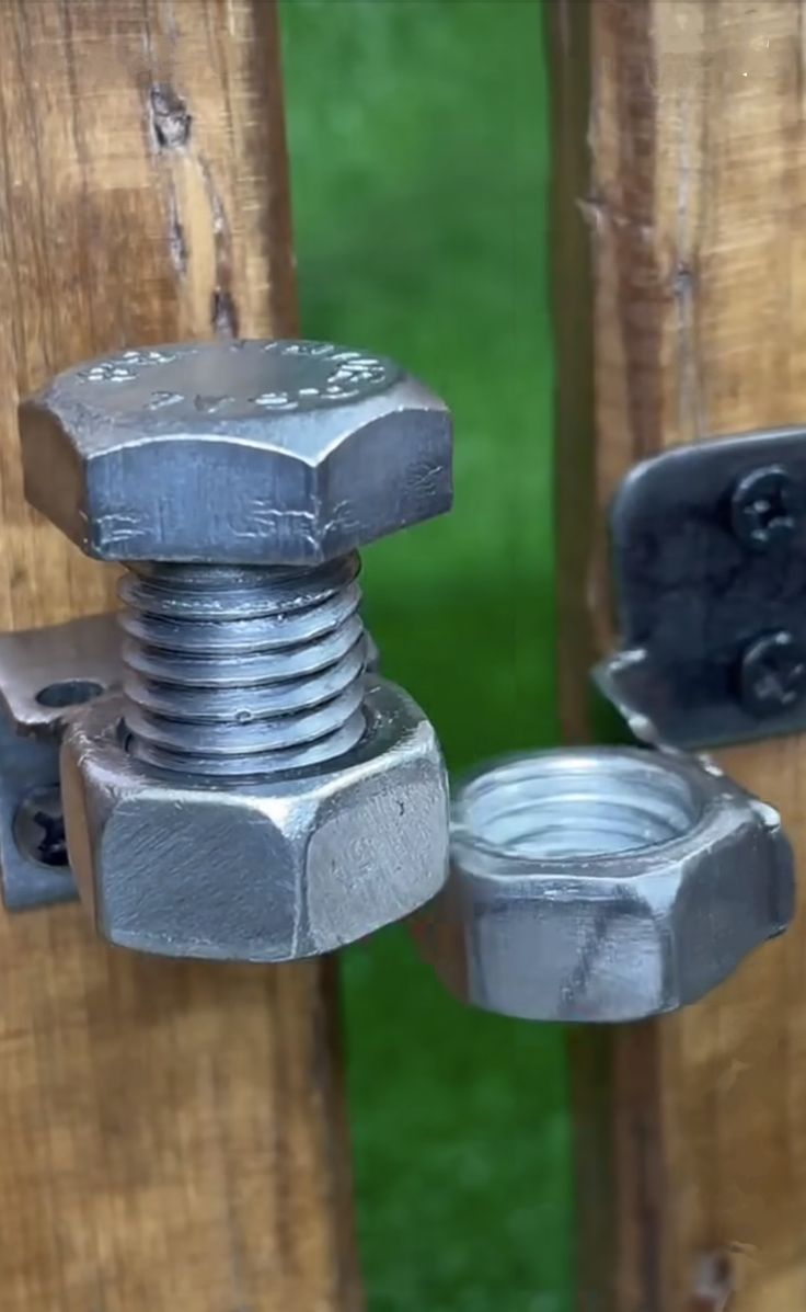 an iron bolt is attached to a wooden door with two screws on each side