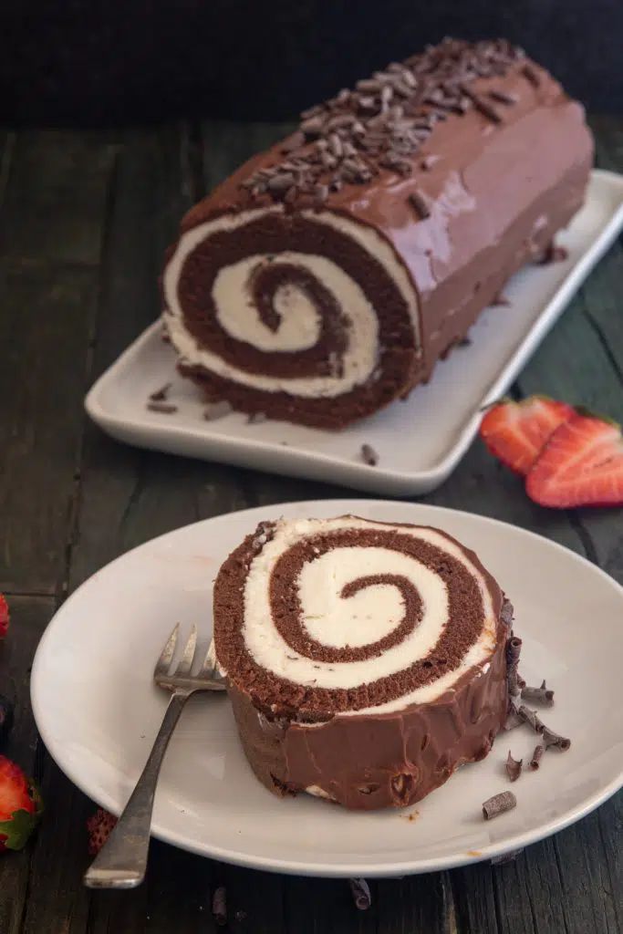 two slices of chocolate roll on plates with strawberries