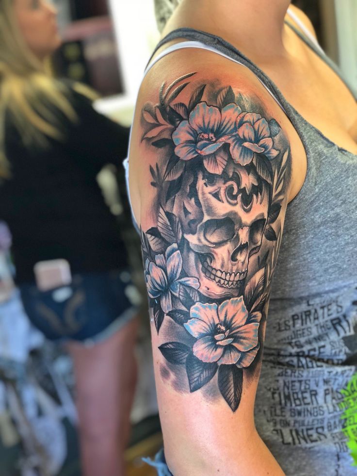 a woman with a skull and flowers tattoo on her arm