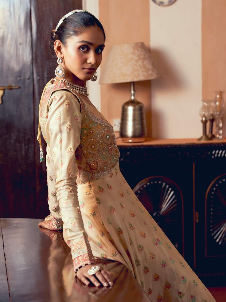 Discover timeless elegance with this classic kalidar jacket set, meticulously crafted from firozi silk zari tissue and jacquard silk banarasi. The design features jharokha-inspired panels intricately embroidered with floral patterns in zari and zardozi, enhanced with dabka, sequins, pearls, and gota texturing for added depth and richness. Complementing the look is a sharara made from crushed tissue, detailed with gota texturing at the hem, creating a gracefully defined and elegant silhouette. Luxury Jacquard Dupatta With Zari Work, Fitted Gold Embroidered Chanderi Fabric, Gold Chanderi Embroidered Fabric With Gota Work, Luxury Traditional Jacquard Dupatta, Traditional Embroidered Jacquard Dupatta, Cropped Jacket, Floral Patterns, Anarkali, Design Features