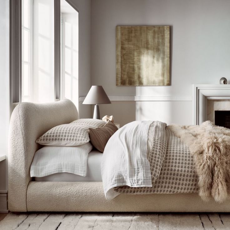 a bed with pillows and blankets on top of it next to a fire place in a room