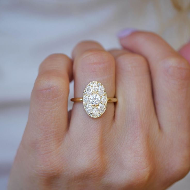 a woman's hand holding an oval shaped diamond ring