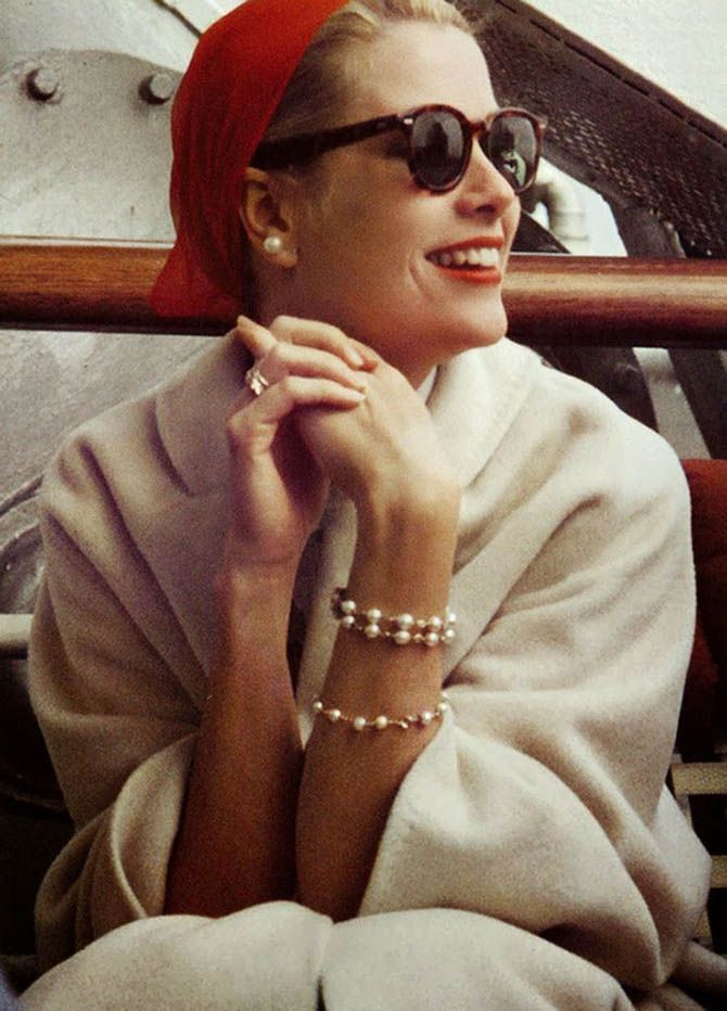 a woman wearing sunglasses and pearls sitting in a boat