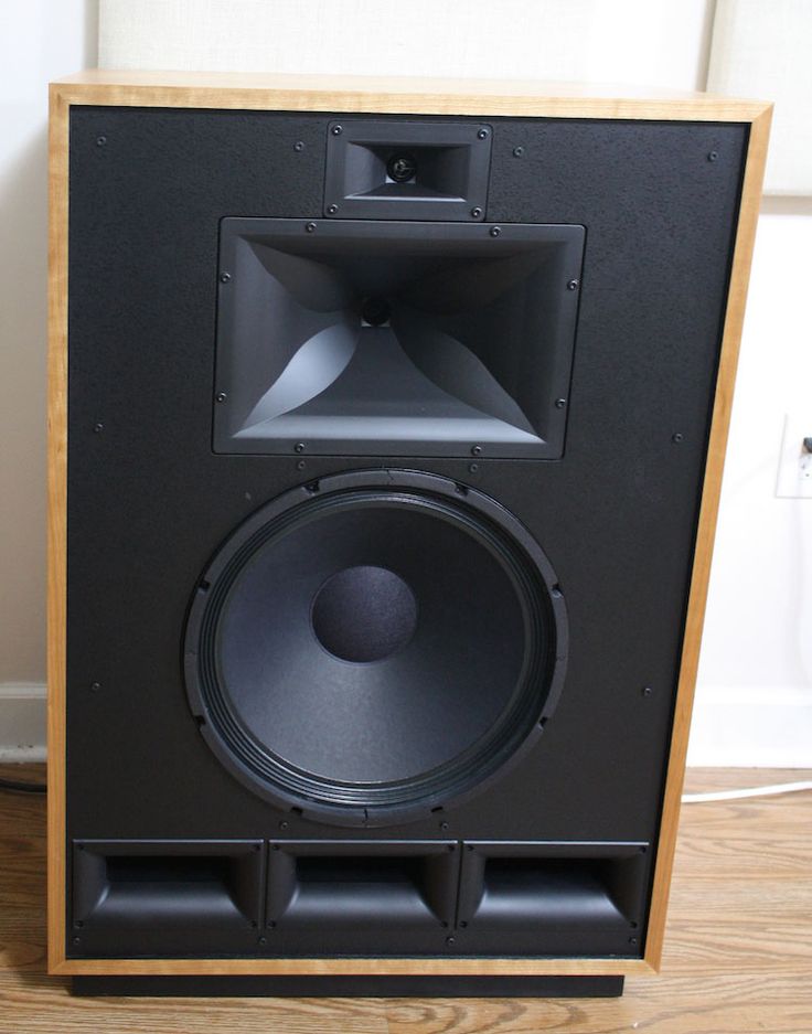 a large speaker sitting on top of a hard wood floor next to a white wall