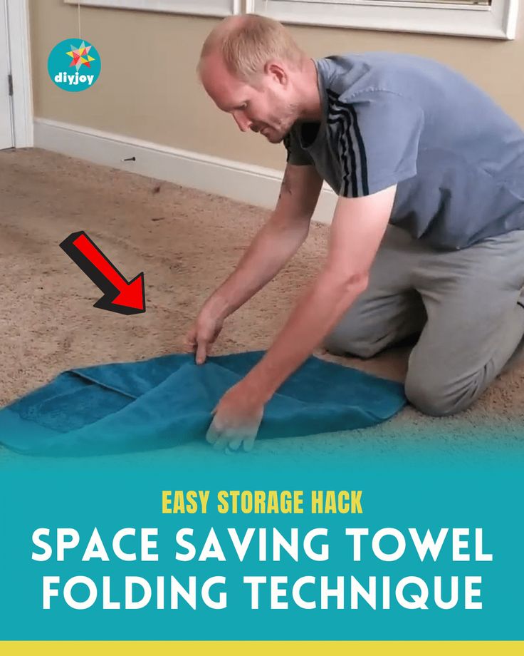 a man kneeling down on the floor with an easy storage hack space saving towel folding technique