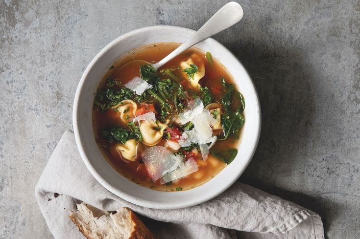 a white bowl filled with soup next to a piece of bread on top of a napkin