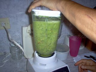 a person is using a blender filled with green liquid