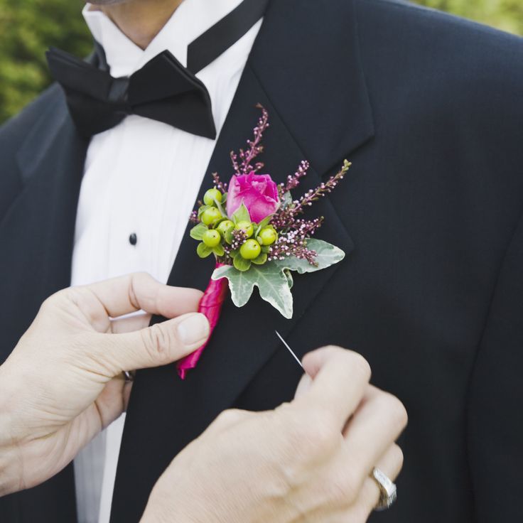 a man in a tuxedo is tying a boutonniere