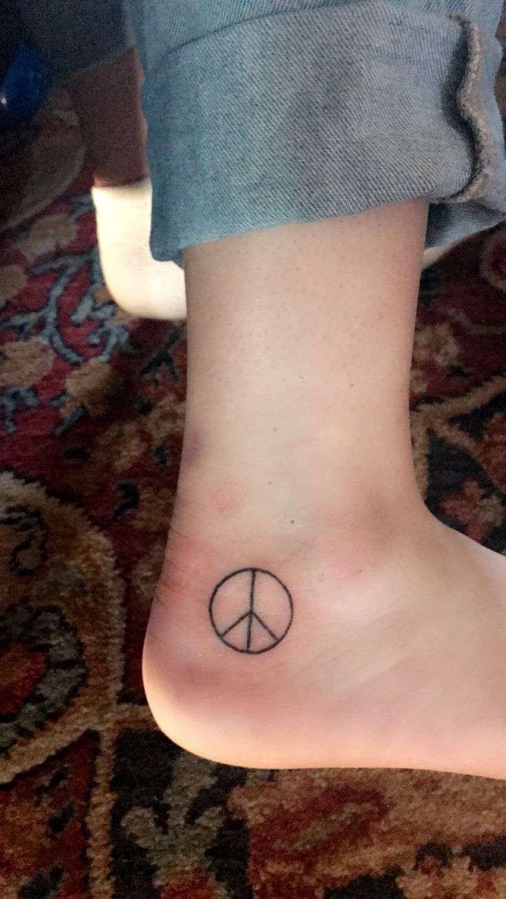 a person with a small tattoo on their foot that has a peace sign on it