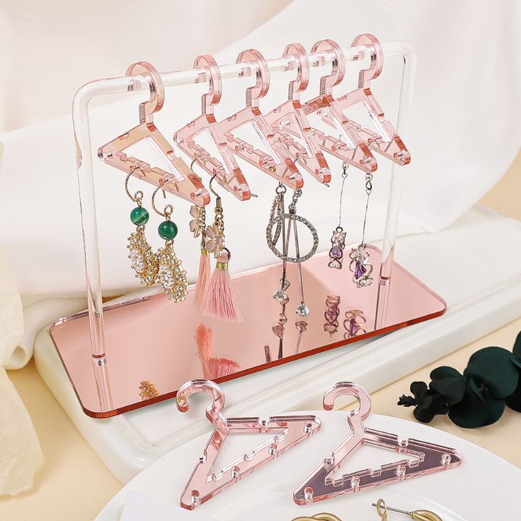 the pink earring holder is holding several pairs of earrings and other jewelry on it