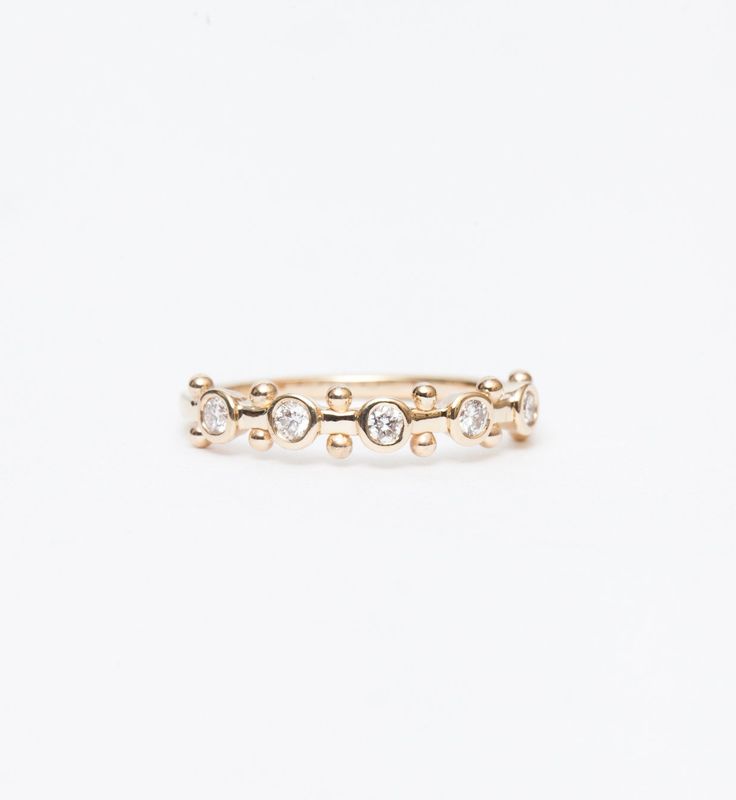 a gold ring with three small diamonds on the front and side, set against a white background