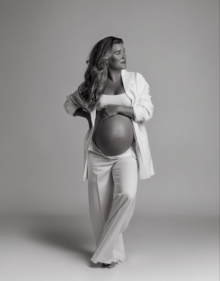 a pregnant woman poses for a black and white photo with her hands on her hips