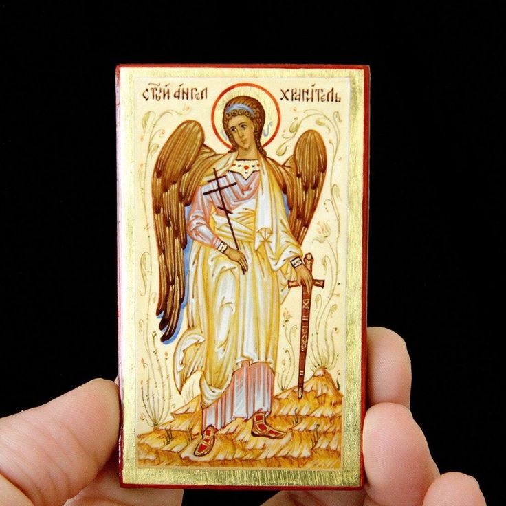 a hand holding a small wooden icon with an angel on it