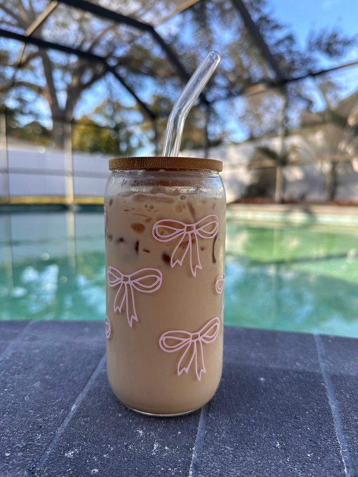 a jar with a straw in it sitting on a table next to a pool