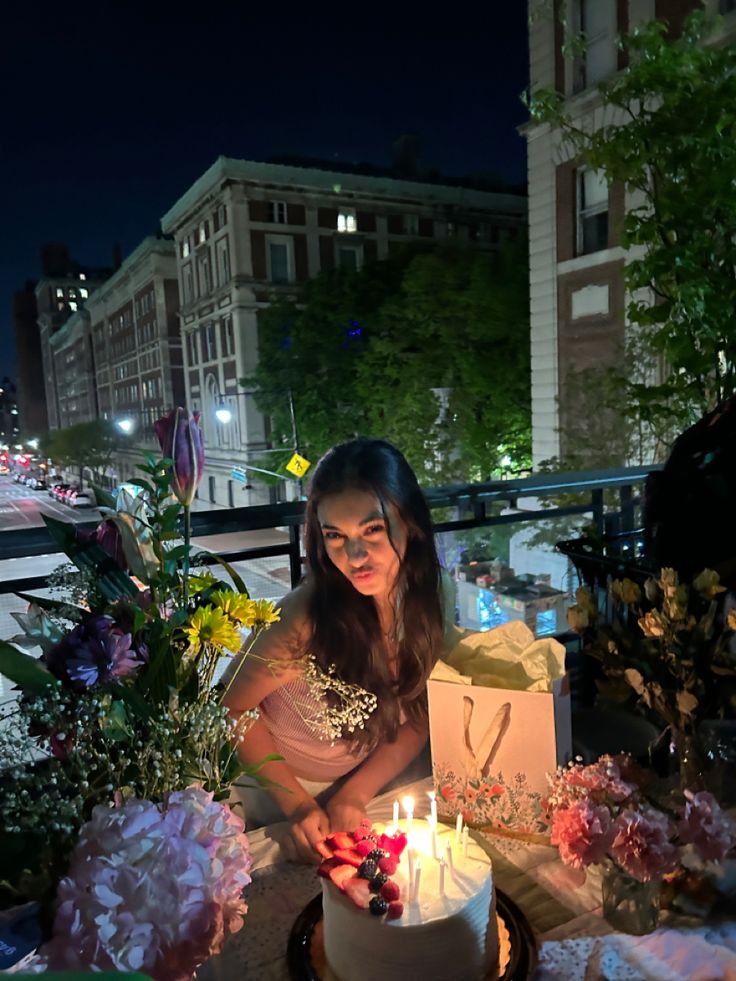 a woman holding a lit candle in front of a cake