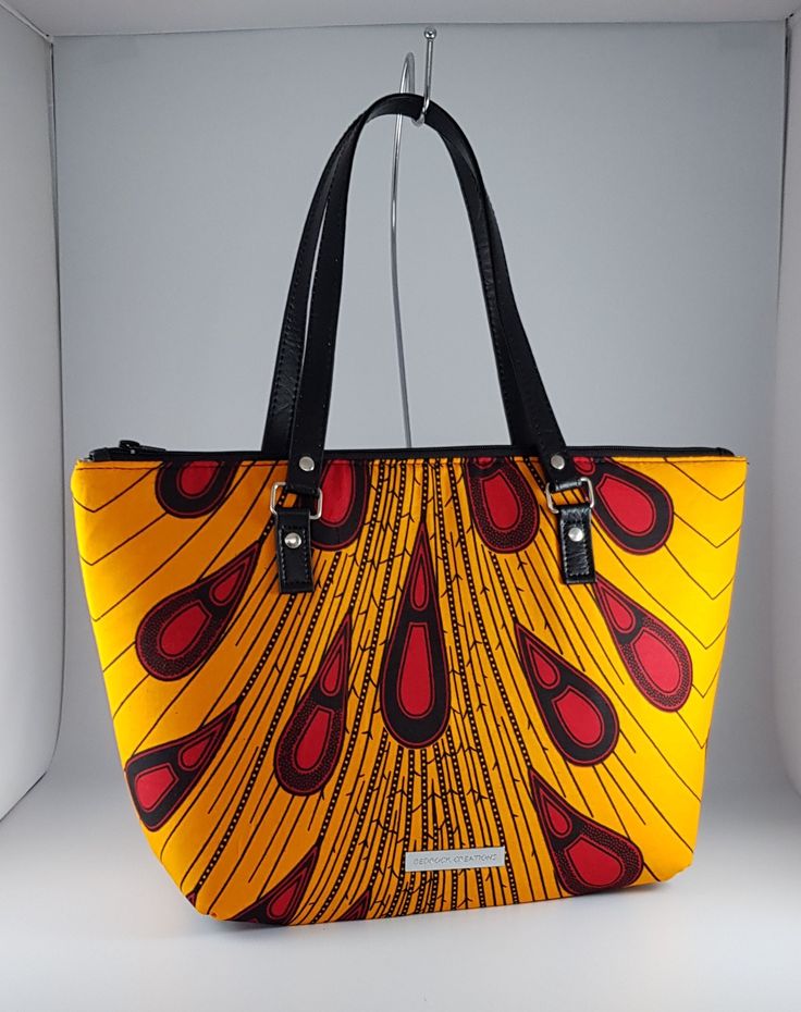 "\"Bag description:  This lovely bag is a perfect size for any occasion, with ample room for all your essentials when shopping, going to the office or on an evening out. The peacock design in yellow and wine also look great against a little black dress brightening the autumn day. This tote bag is a combination of Ankara African fabric and faux leather, fully lined waterproof canvas fabrics. The handles are long enough to fit comfortably on the shoulder or held by hand. Internally, this bag is fully lined with waterproof canvas and zippered pocket which fits your phone or other valuables. This bag is closed with a durable zip. Bag Style: Tote Fabric: African Wax Print Fabric - Ankara yellow and wine print fabric. 100% Cotton Lining: Waterproof canvas Hardware: Chrome  Handles: 24 inches in Trendy Yellow Bag With Removable Pouch, Trendy Yellow Double Handle Bag, Yellow Handheld Bag For Shopping, Yellow Handheld Shopping Bag, Trendy Yellow Shoulder Bag, Yellow Handheld Bag, Trendy Yellow Box Bag With Removable Pouch, Yellow Satchel Bag For On-the-go, Yellow Satchel With Top Carry Handle For On-the-go