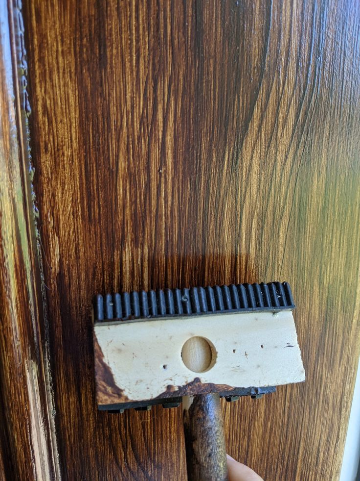 a person is holding a hammer in front of a door with wood grain on it