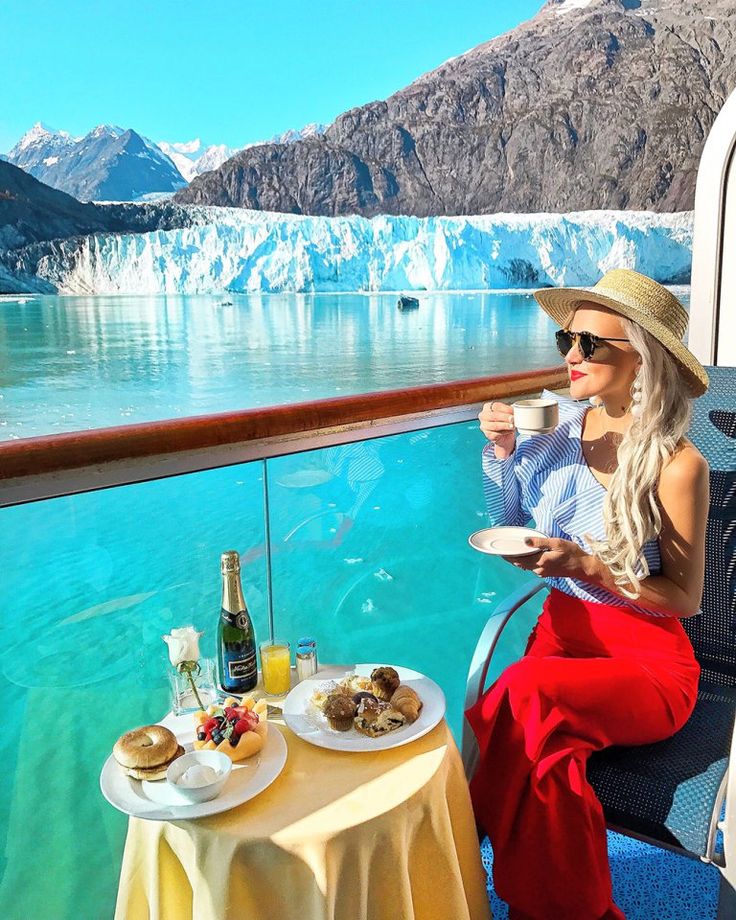 a woman sitting at a table with food and drinks in front of an iceberg