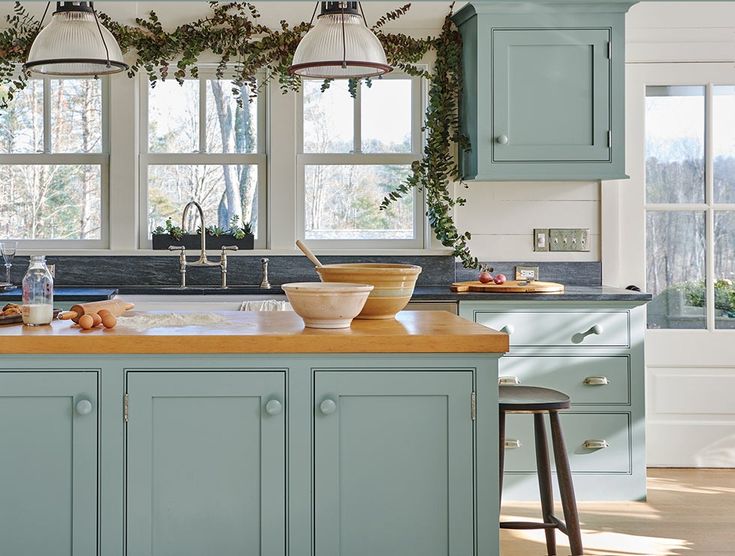 a kitchen with blue cabinets and wooden counter tops, two hanging lights above the island