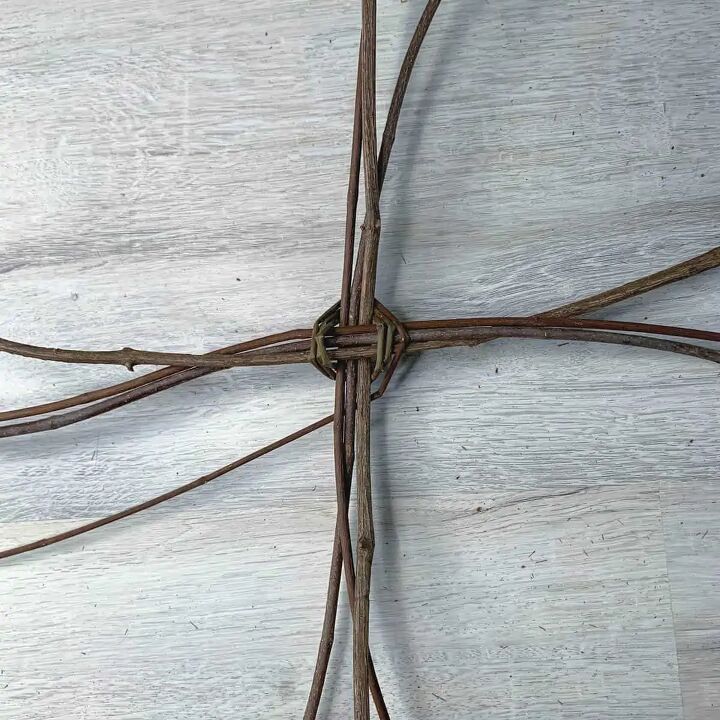 a cross made out of barbed wire sitting on top of a white wooden tablecloth