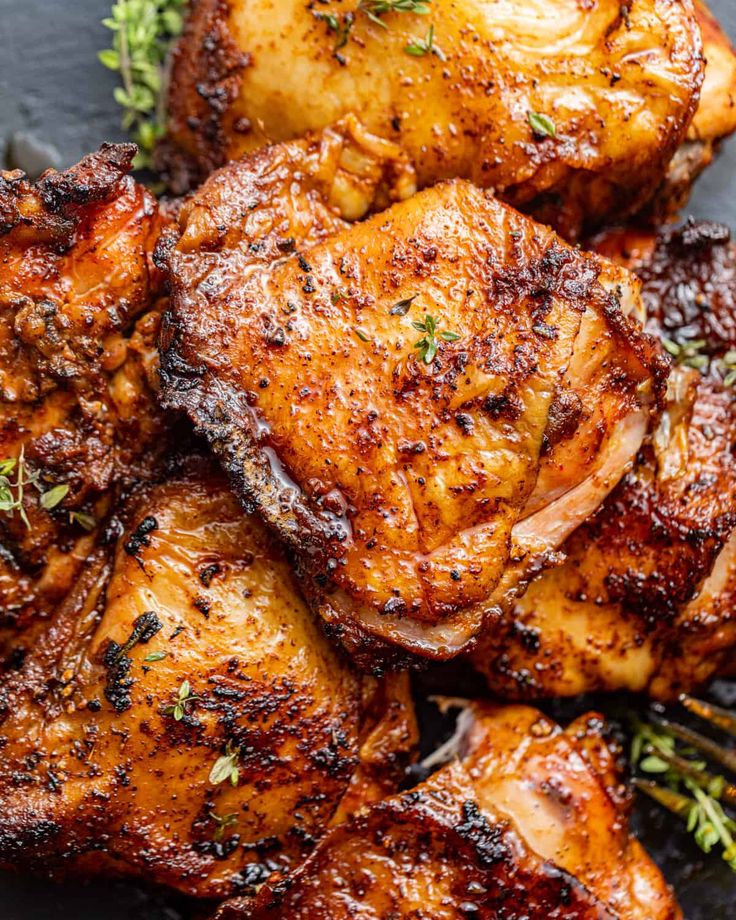 grilled chicken with herbs and spices on a black plate, close - up view