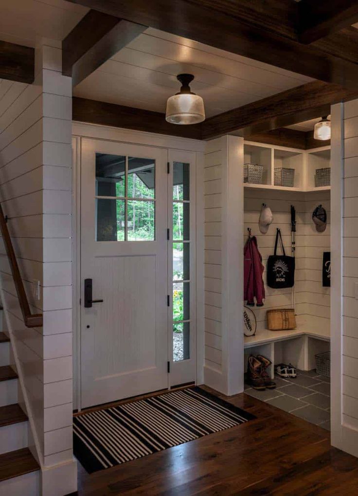 an entryway with white walls and wood flooring next to a wooden stair case