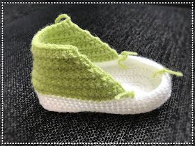 a pair of crocheted baby shoes sitting on top of a black tablecloth