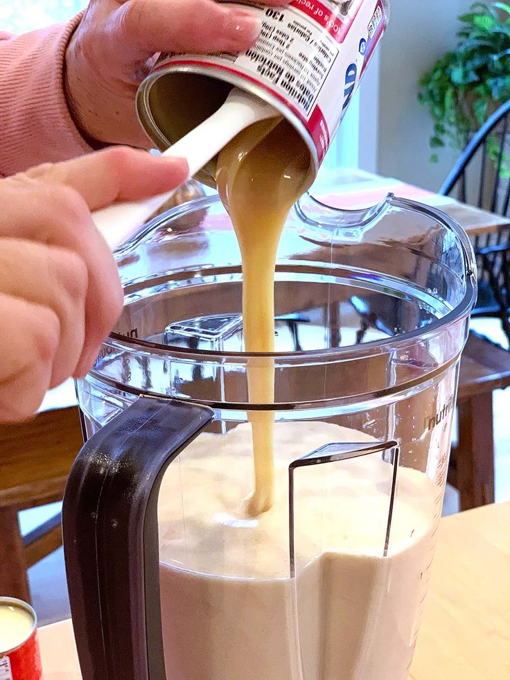 a person pouring milk into a blender